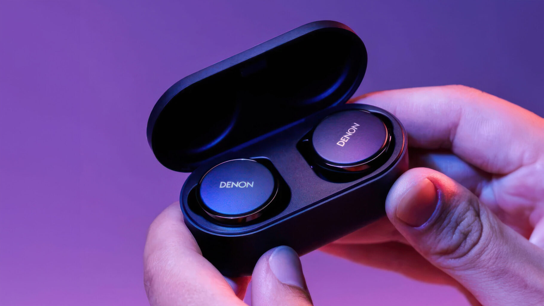 Denon PerL Pro 2 a person holding a black box with two round buttons Denon PerL Pro