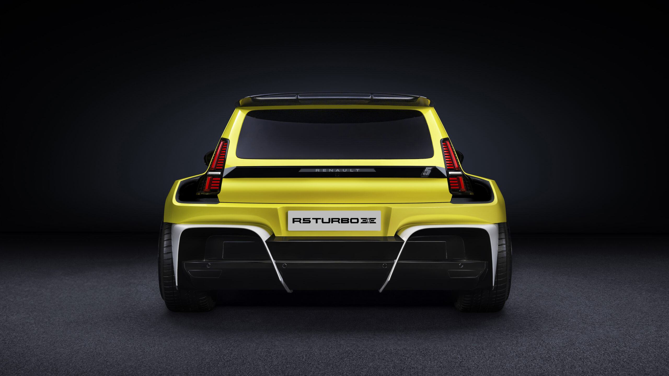 Renault R5 Turbo 3E: Fra rally-helt til elektrisk miniraket 2 Renault R5 Turbo 3E sett bakfra. Den brede hekken, de vertikale baklysene og den markante spoileren understreker bilens racing-DNA. Den elektriske hot hatchen har en futuristisk, men retro-inspirert look.