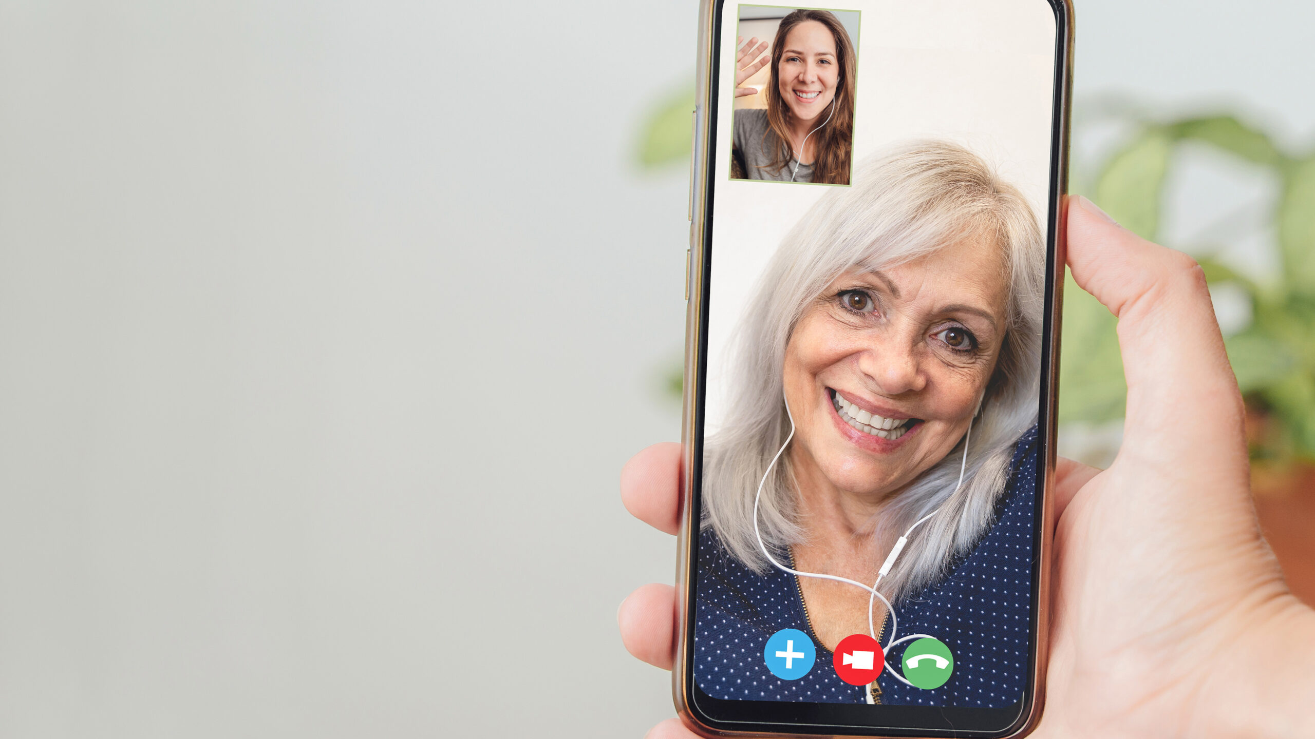 Happy senior and daughter talking on video call with mobile phone - Focus on hand holding smartphone