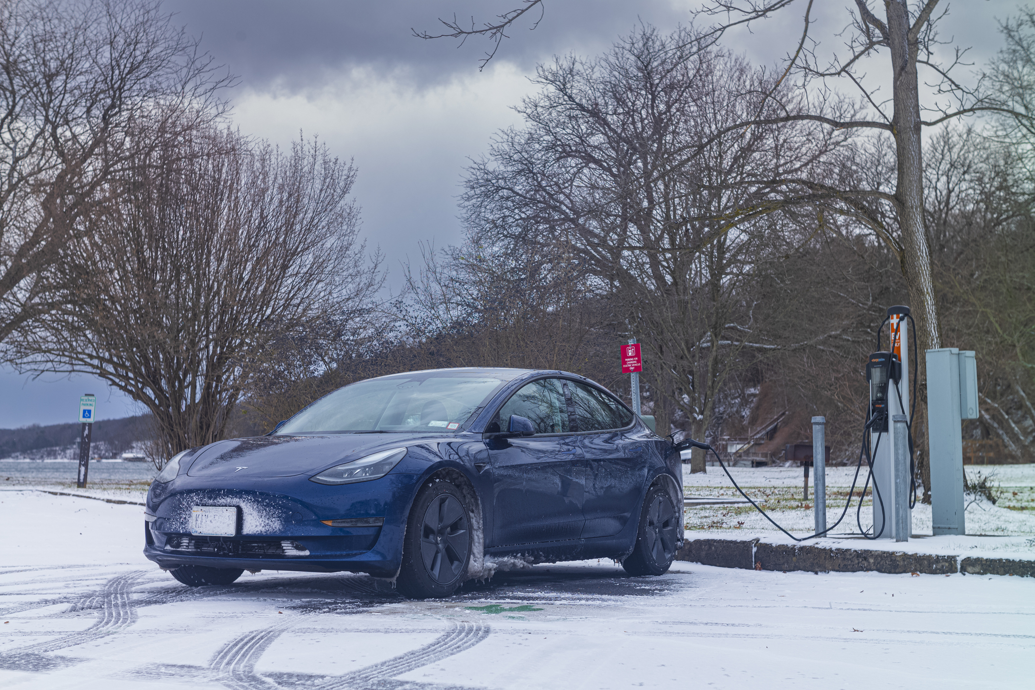Trumansburg, NY, USA - Jan 14, 2023: A Tesla Model 3 charges at a Level 2, ChargePoint station at Taughannock Falls State Park during a cold January winter. day.